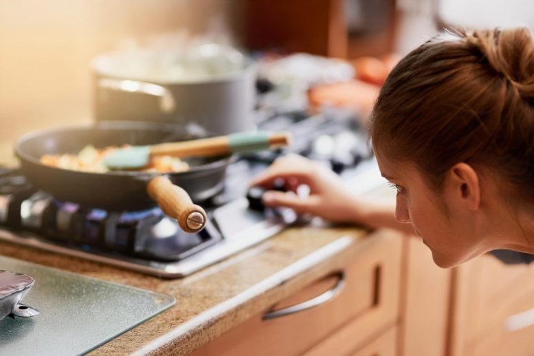 Woman Cooking Adjusting Gas Kitchen Stove